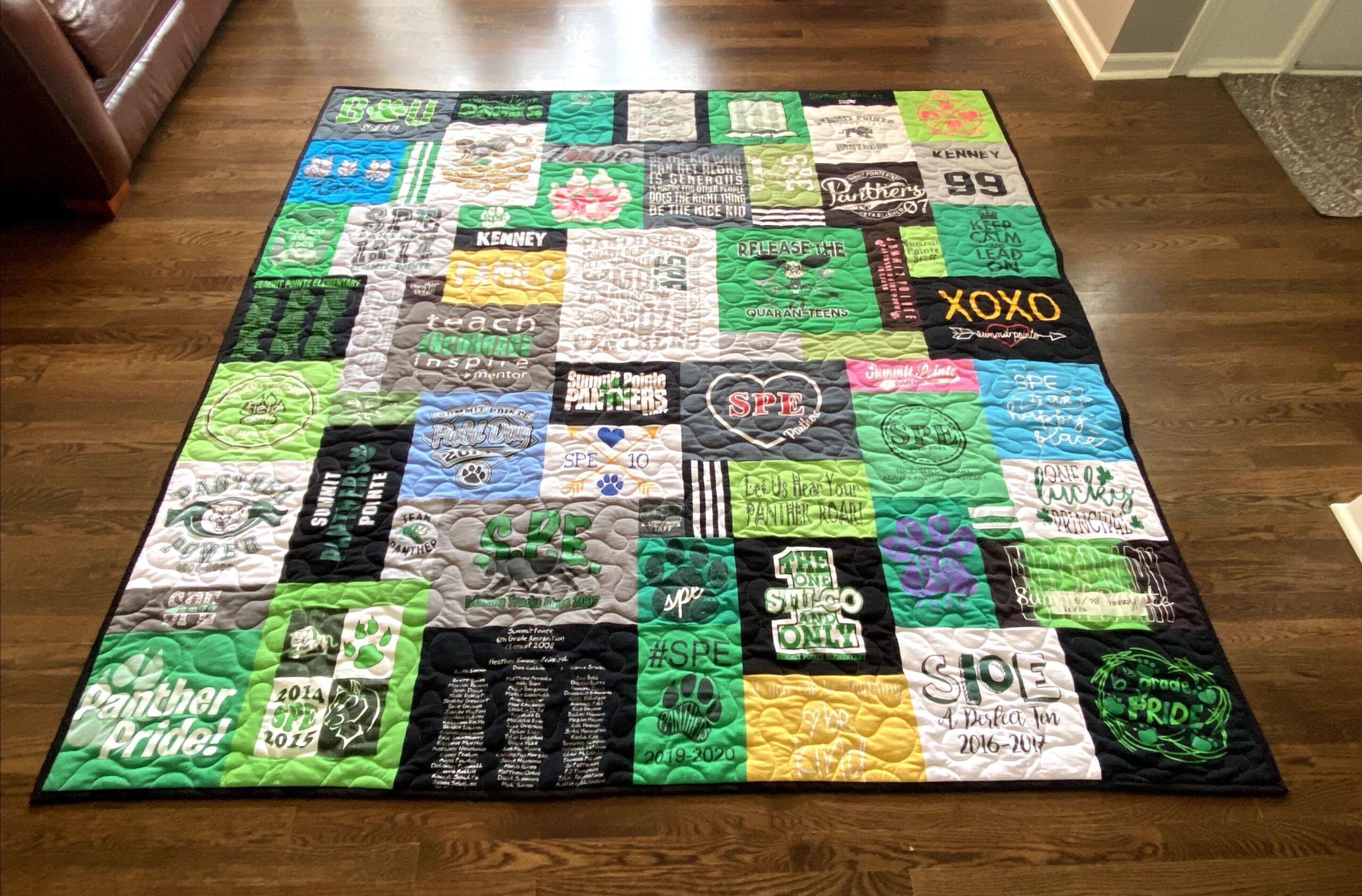 A quilt made out of shirts on the floor